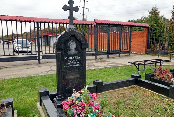 Памятник с крестом на верхней части с ограждением из гранита